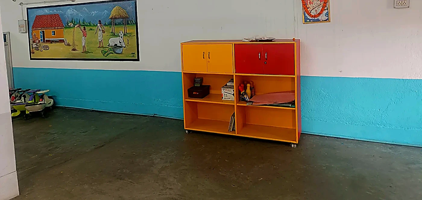Indoor play space with yellow toy cupboard and village art mural